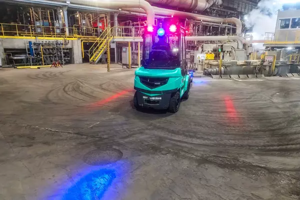 Photo: Aurubis: Green forklift truck drives in a hall and has red warning lights on