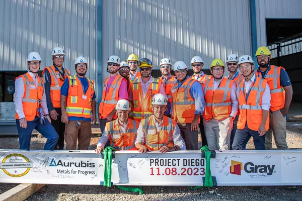 Photo: Aurubis: A group of people in safety vests pose for a group photo in front of a large, painted steel girder