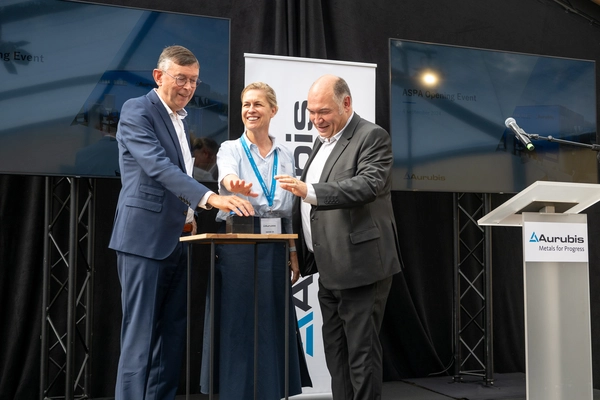 Photo: Aurubis: Two men and a woman standing on a stage, holding out their hands