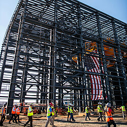 Photo: Aurubis: Scaffolding of a hall that is currently under construction, the USA flag and people can be seen on the construction site