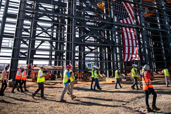 Photo: Aurubis: Scaffolding of a hall that is currently under construction, the USA flag and people can be seen on the construction site